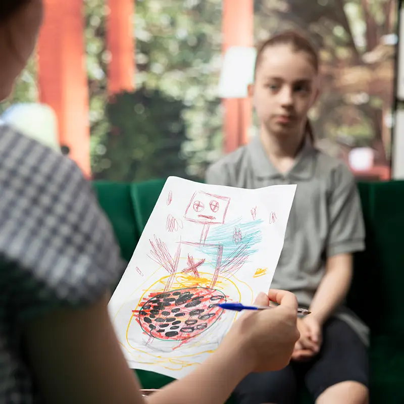Supporto personalizzato nel percorso di apprendimento Tutor che analizza un disegno insieme a una ragazza in un contesto educativo, durante un momento di ascolto e supporto individuale